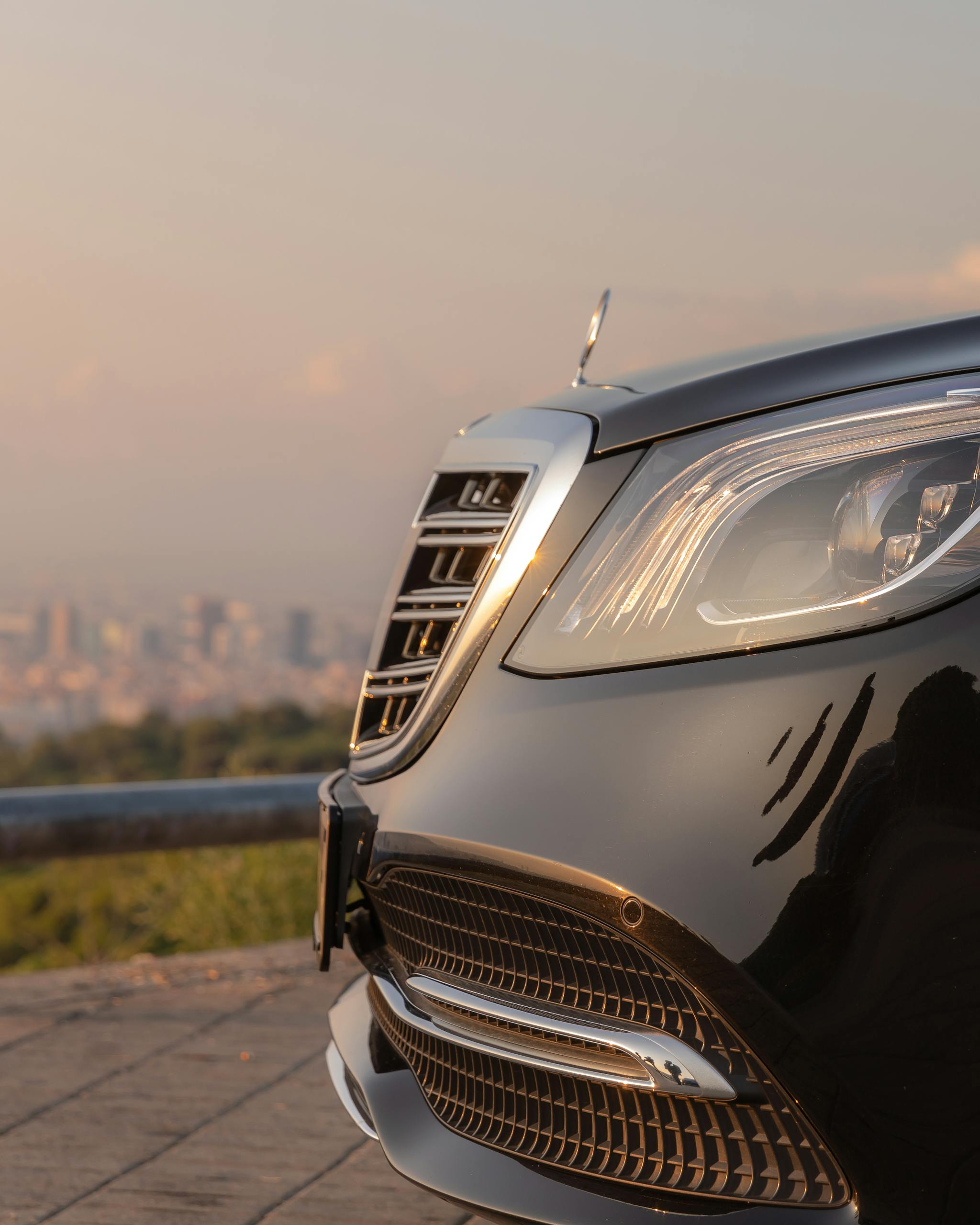 Close-up of a luxury Mercedes Benz front, highlighting its chrome details and sleek design during twilight.